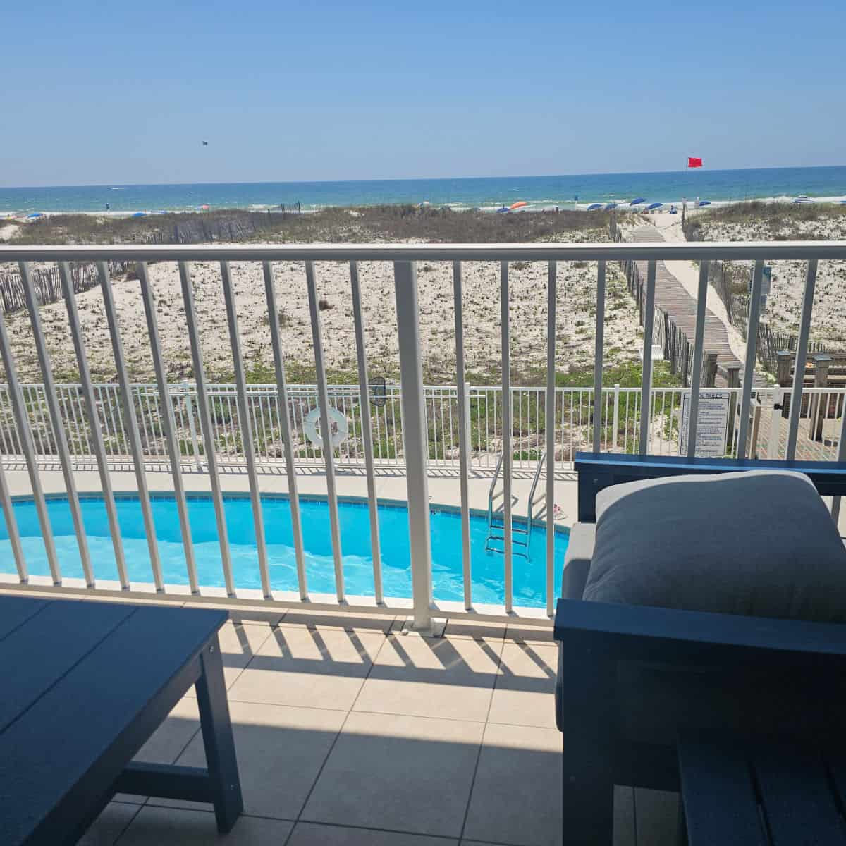 Balcony with chairs looking out over the pool and beach access, Gulf waters in the background