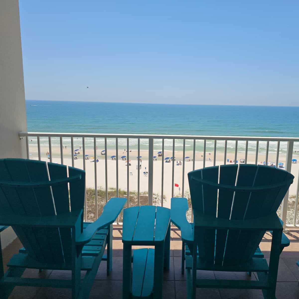 balcony with Adirondack chairs looking out to the beach with Gulf waters in the background