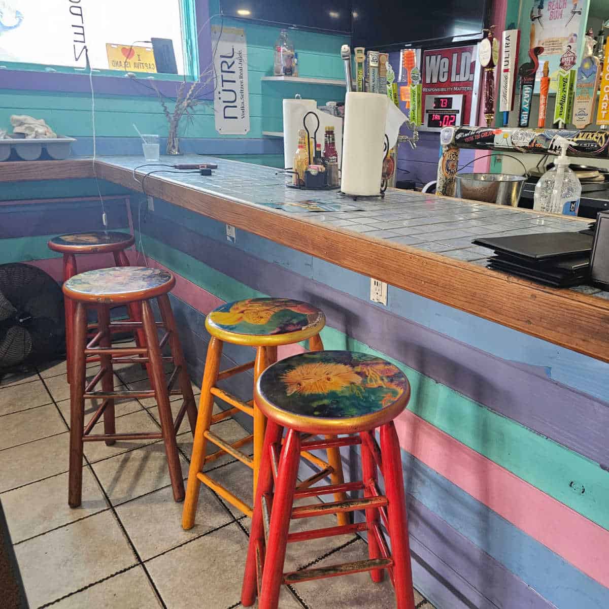 indoor bar with tall round stools, multiple colored rows of wood under the car