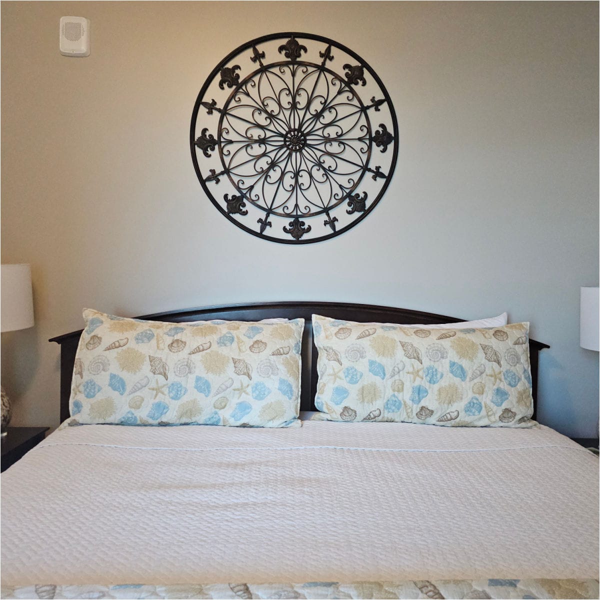 bedroom with shell pillows on the bed, metal art above the bed