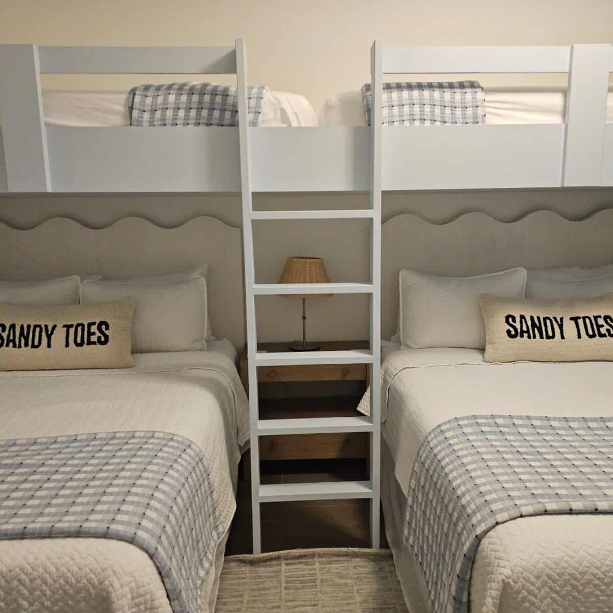 bunkbeds with white linens and blue and white blankets, pillows that say Sandy Toes