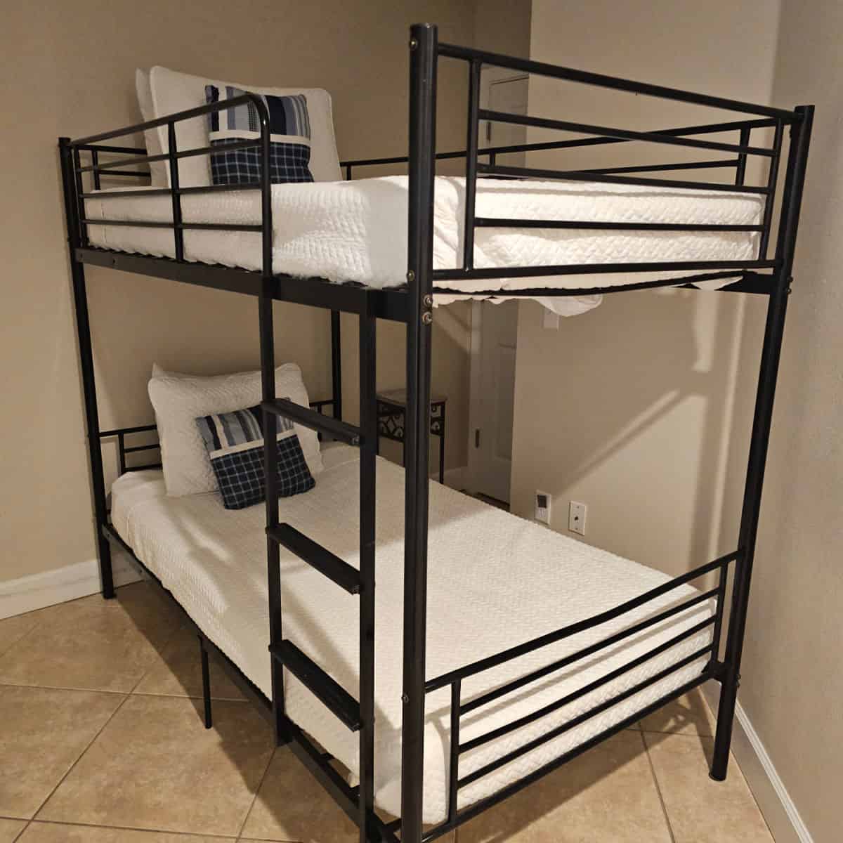 black metal bunk bed with white linens and black and white pillows
