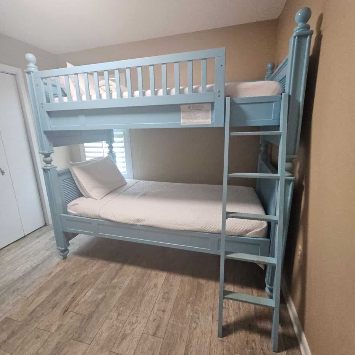 light blue painted bunk bed with ladder on one side up to the 2nd bed