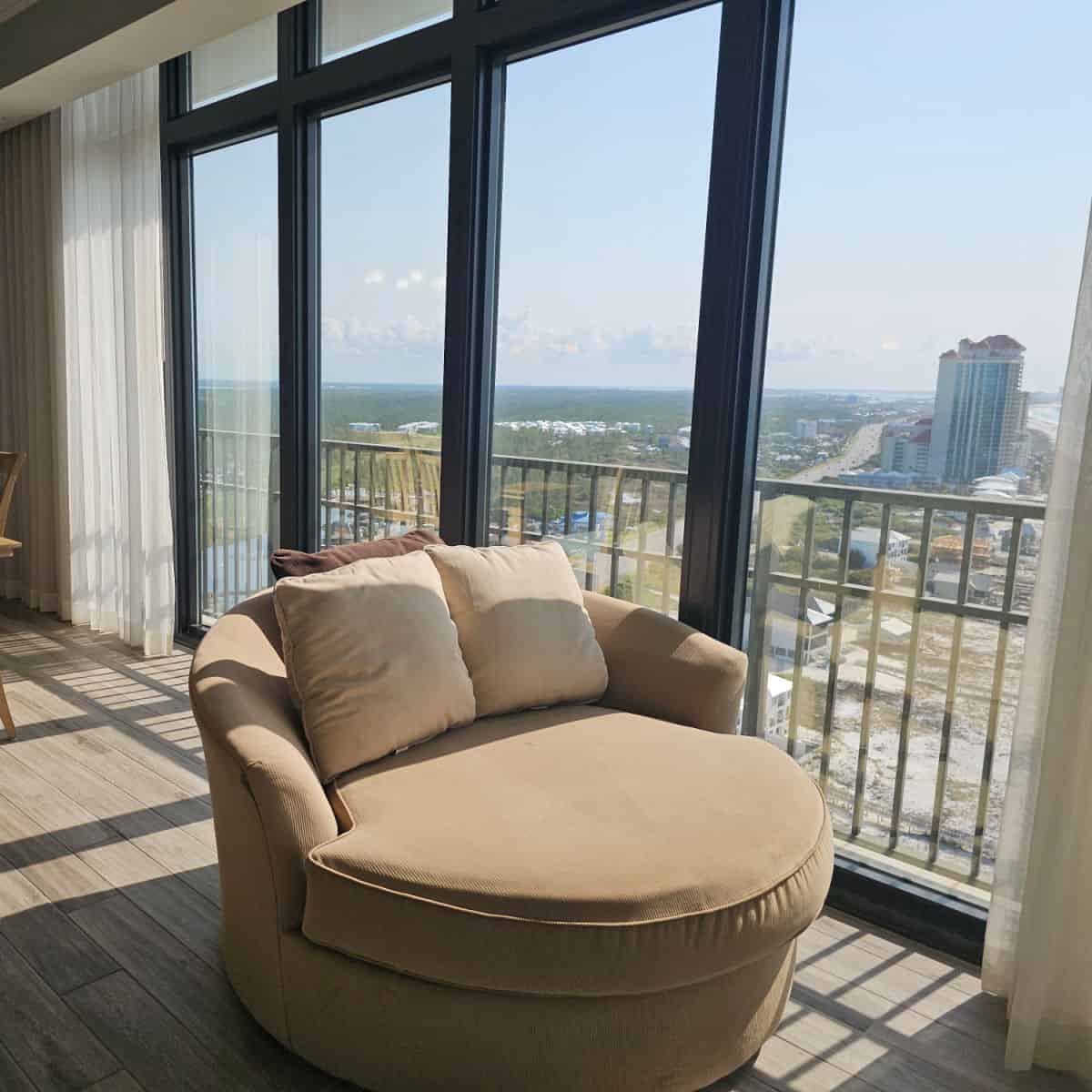 comfy chair next to a window looking out large windows to the beach and Orange Beach