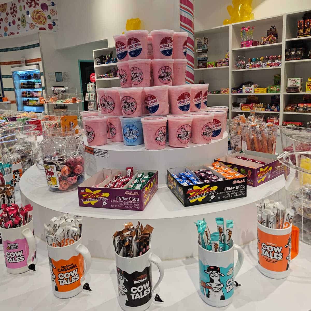 long white table with buckets of candy including cow tales, cotton candy, and more