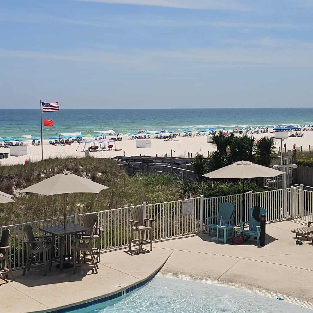 looking over the pool deck to thie sand beach with umbrellas along the Gulf shorelines