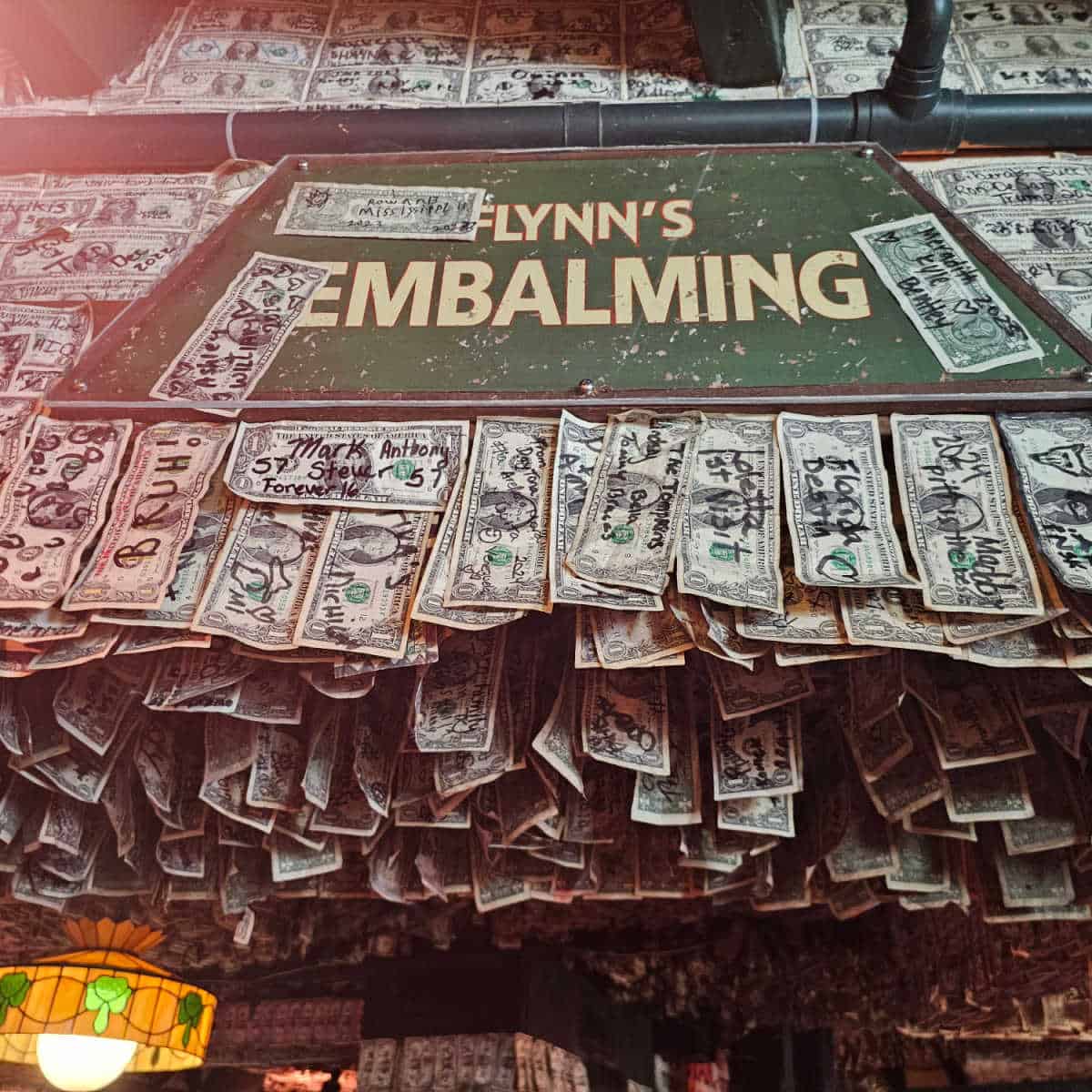 Flynn's Embalming sign surrounded by dollar bills