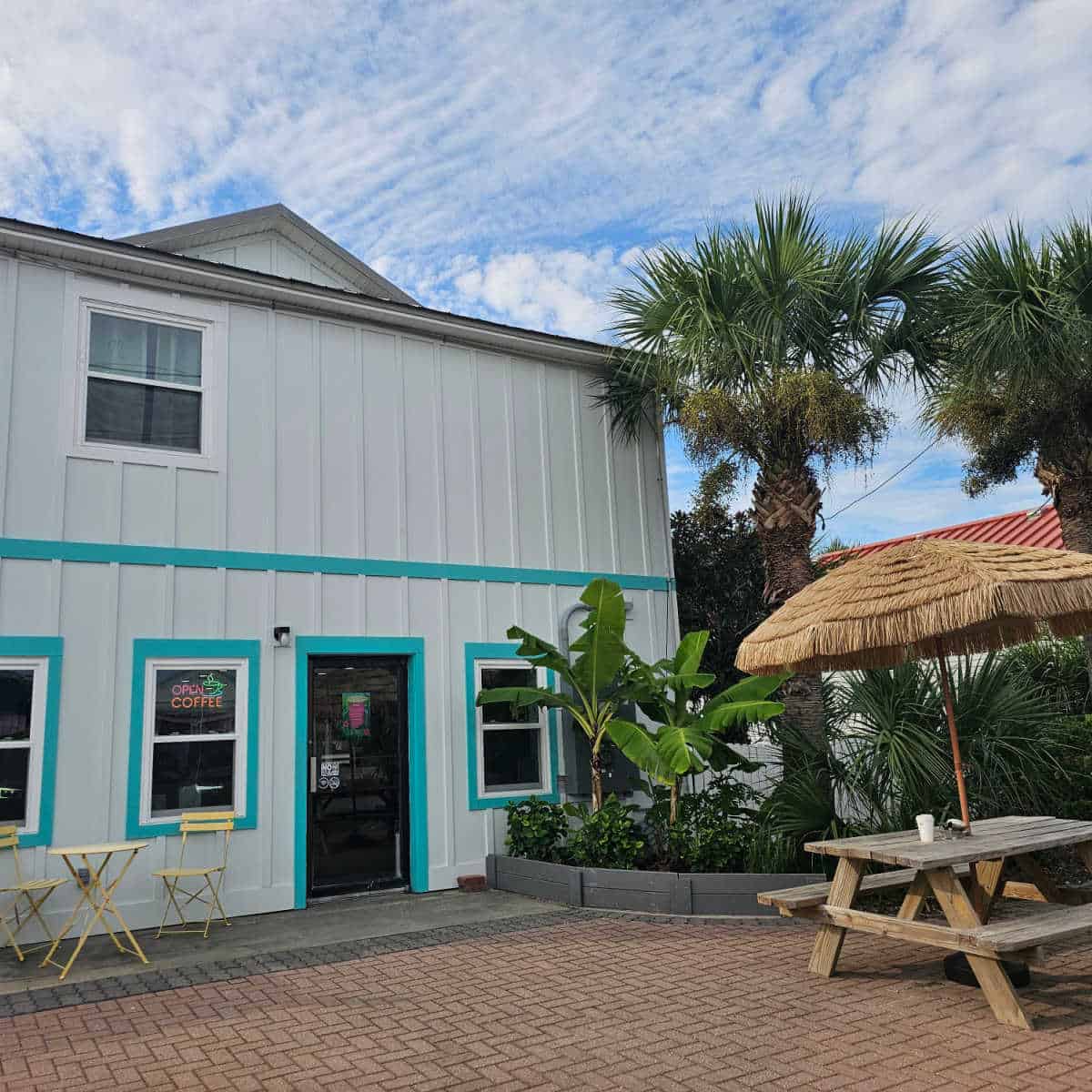 two story white building with turquoise trim, umbrella over a picnic table