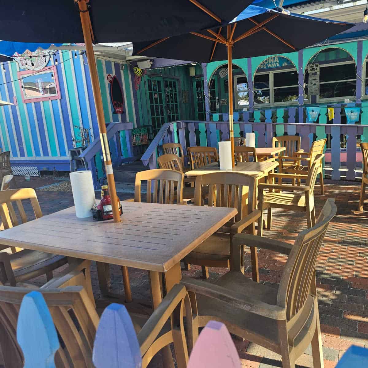 outdoor tables with blue umbrellas next to a striped blue and purple and turqouise building