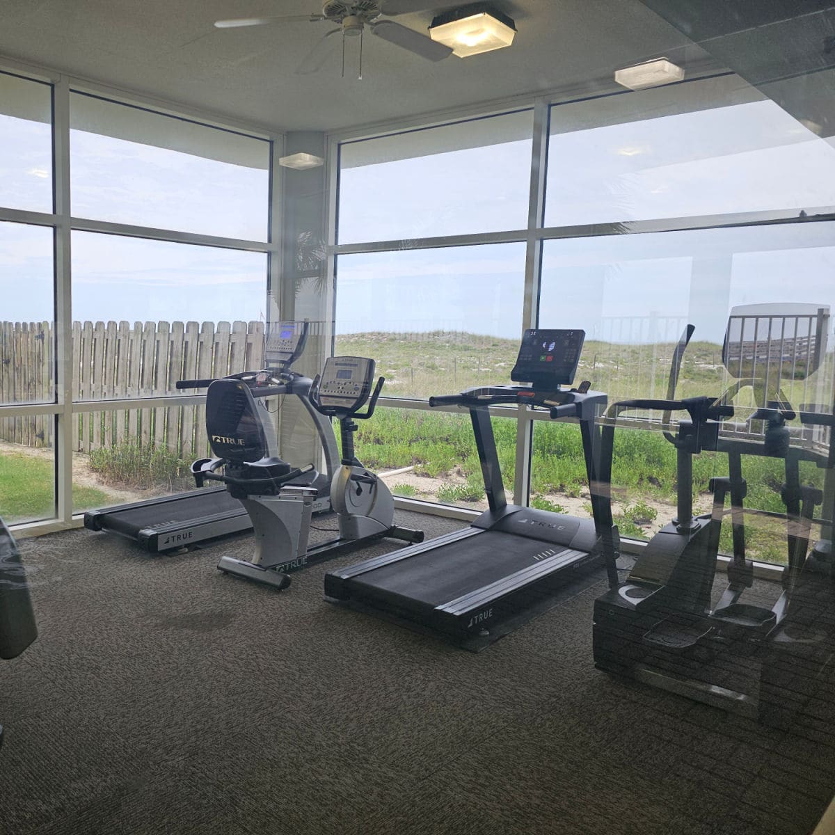 fitness center with a couple of treadmills and eliptical, and exercise bike