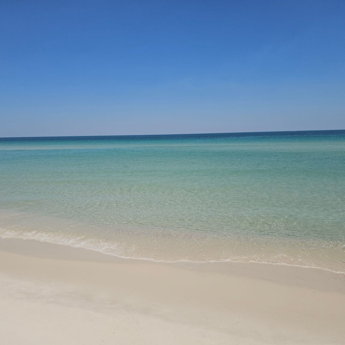 calm gorgeous turquoise waters leading up to a white sand beach