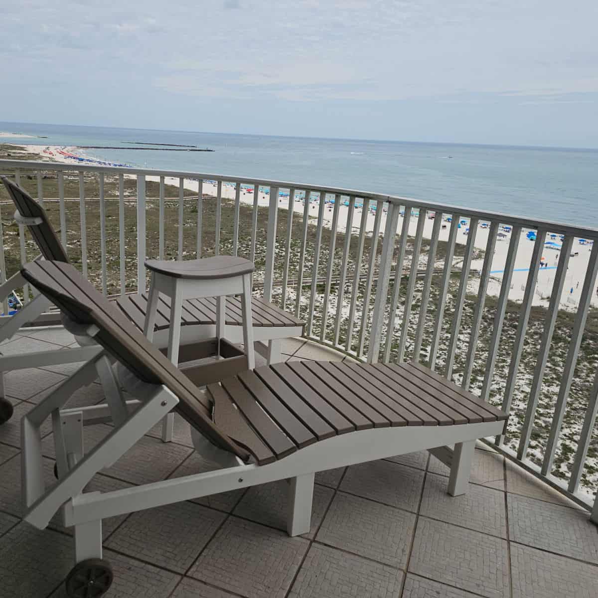 balcony with two lounge chairs looking out over the beach and Gulf waters