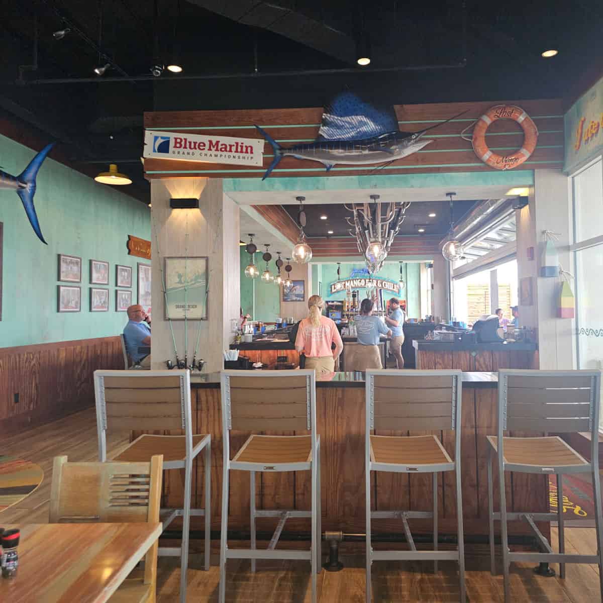 Blue marlin grand championship sign, blue marlin fish, and life ring over an indoor bar with tall bar seats