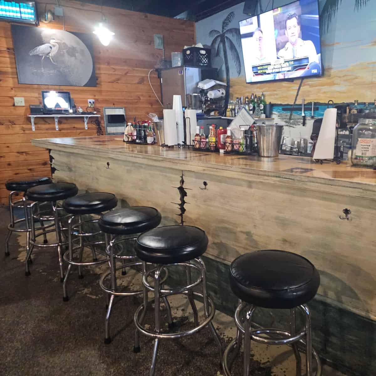 bar with leather topped stools, tv behind the bar