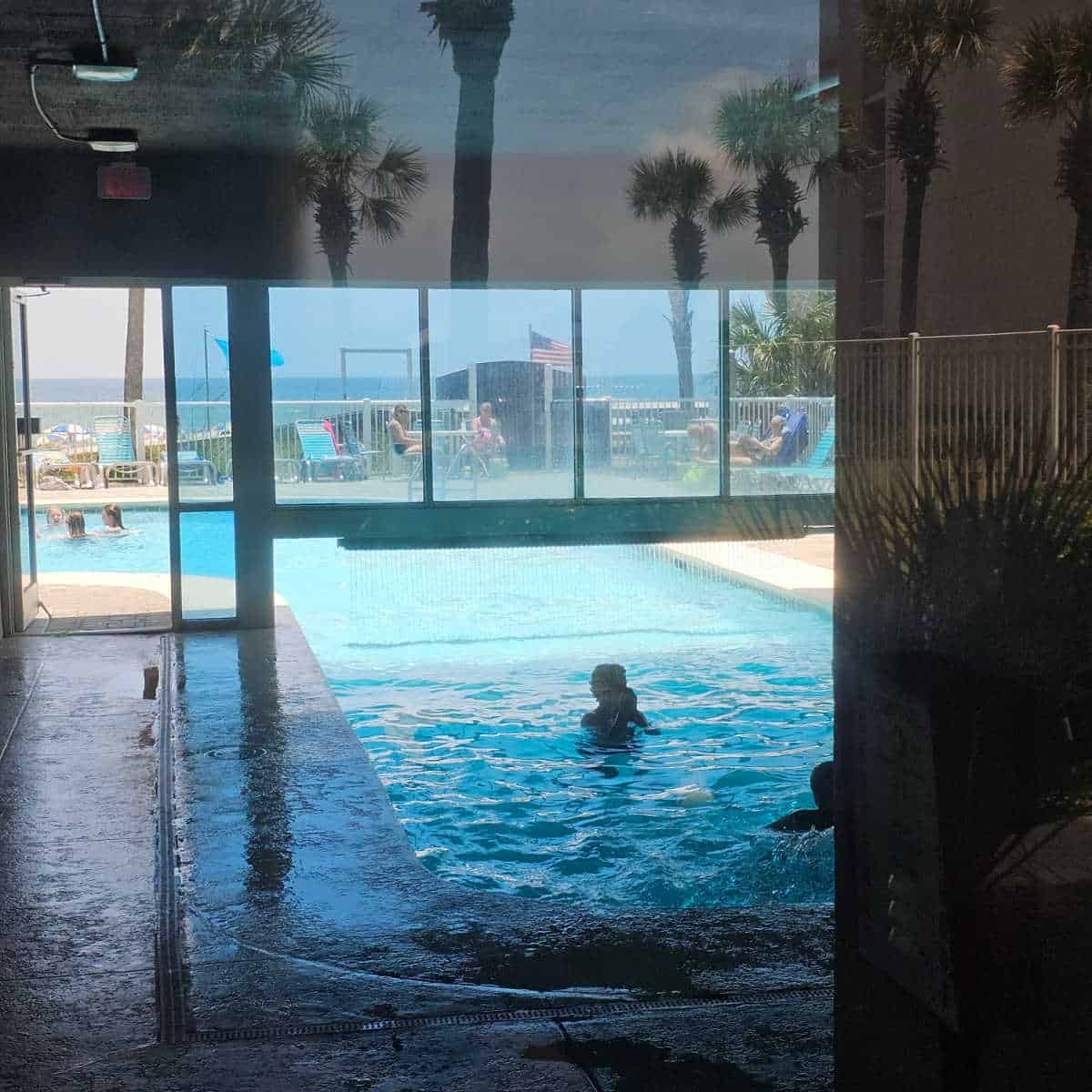 indoor pool that flows into the outdoor pool, people on the outdoor pool deck
