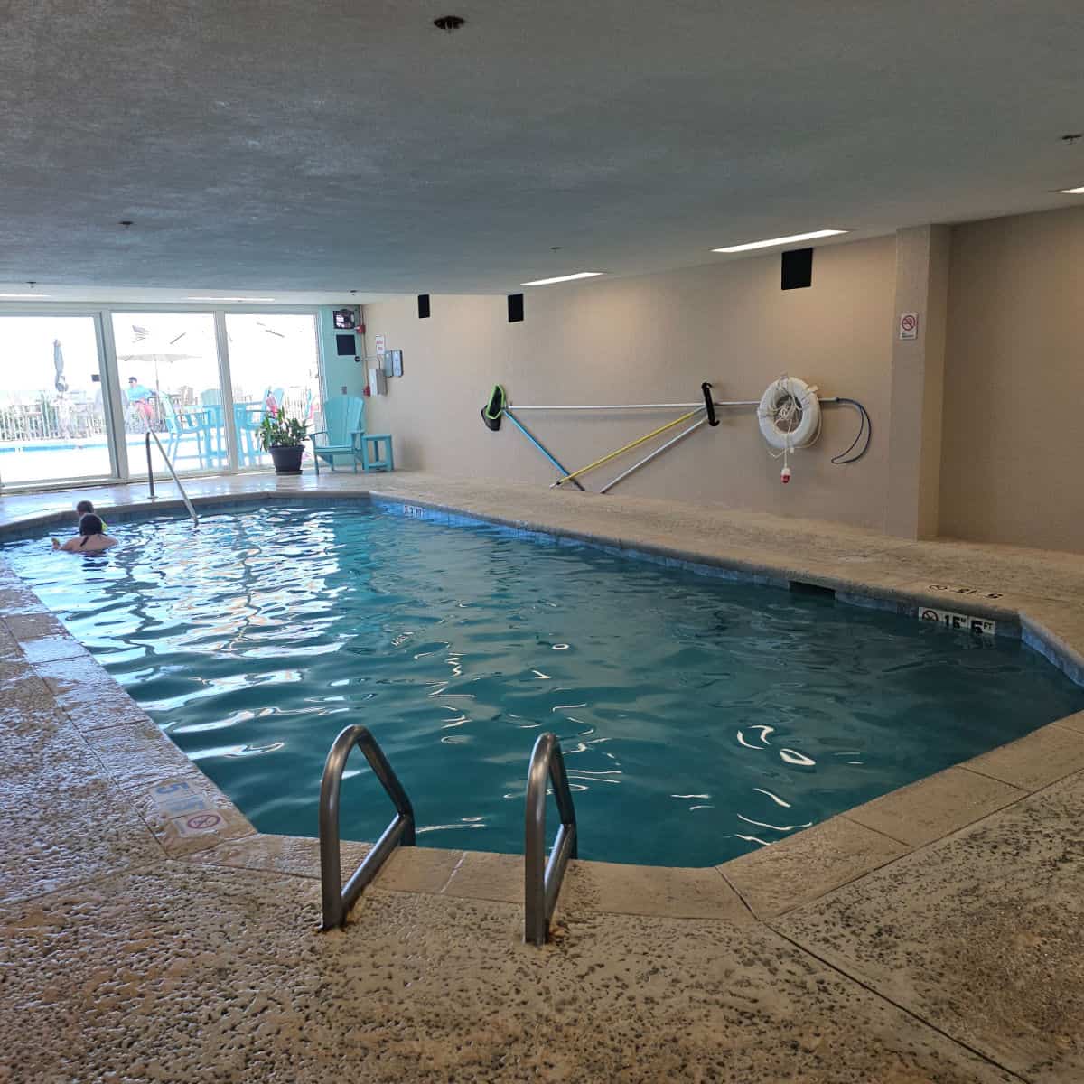 indoor swimming pool with two people at the far end