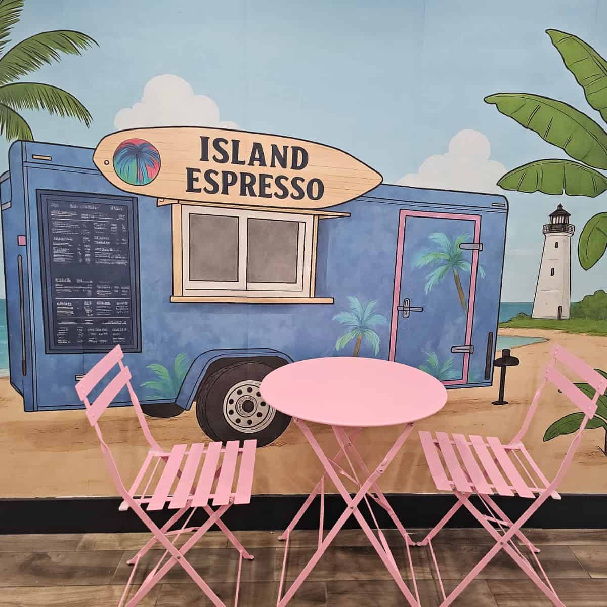 Pink table and chairs with an island espresso cart mural behind them