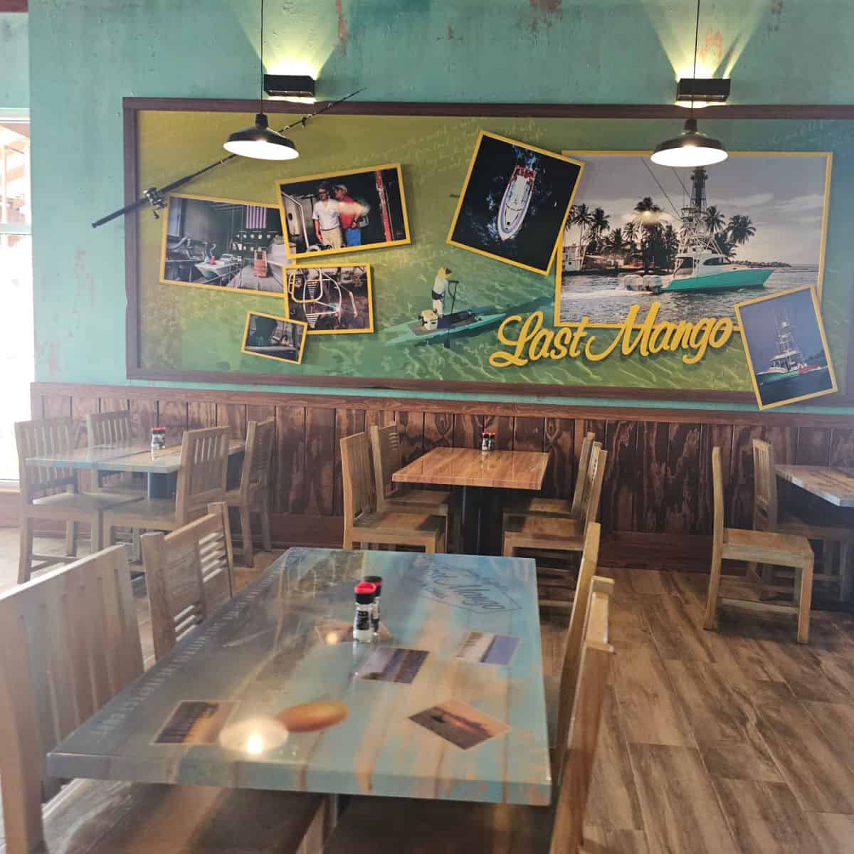 last mango on the wall with a fishing pole and boat pictures, above tables and chairs