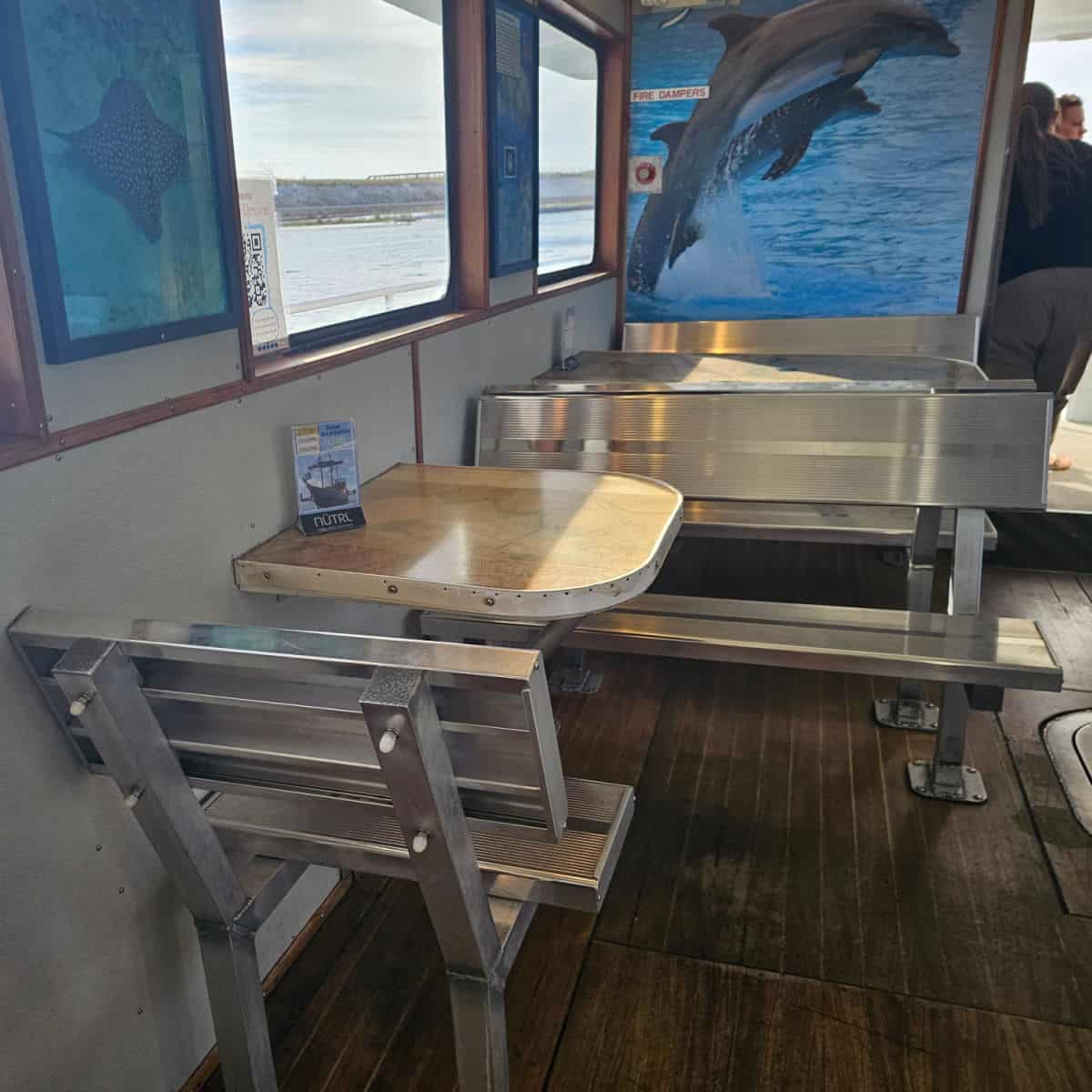 indoor seating with a table with a single chair and bench seating by a large dolphin photo