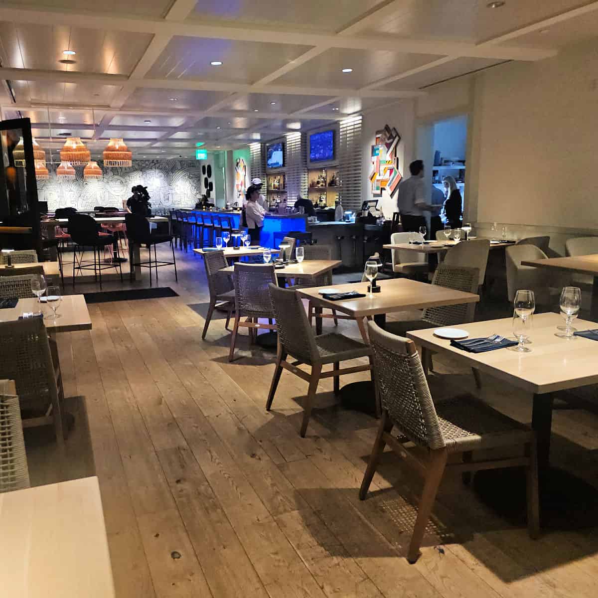 indoor seating with tables and chairs leading towards an indoor bar, servers walking through the room