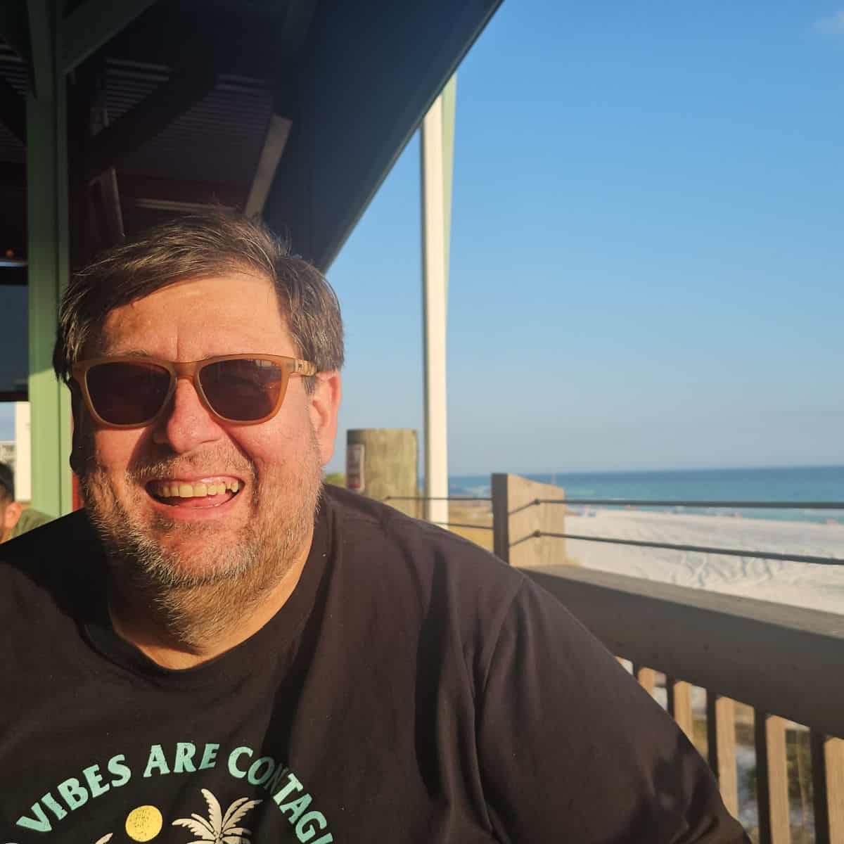 John smiling with the Gulf and white sand in the background