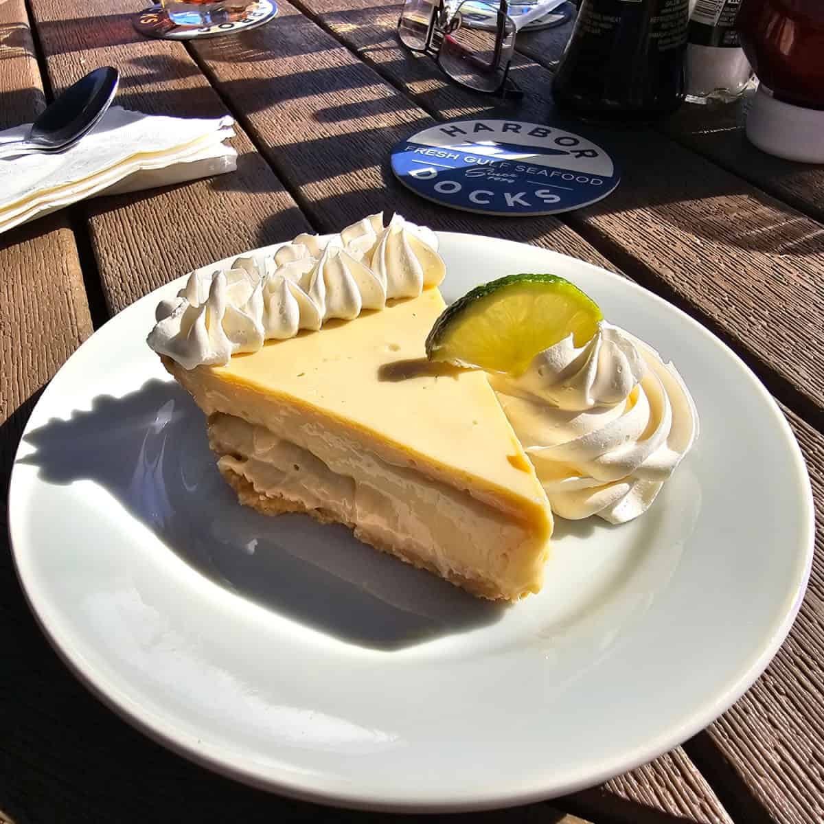 key lime pie on a white plate with a harbor docks coaster behind it