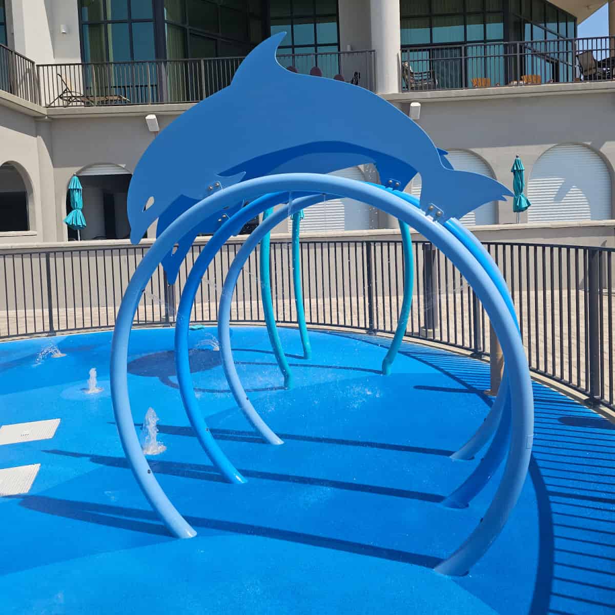 kids water play area with a dolphin structure and water coming out of the play area