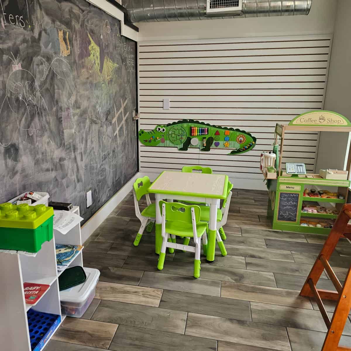 kids play area with a large chalkboard wall, alligator on the wall, tables and toys