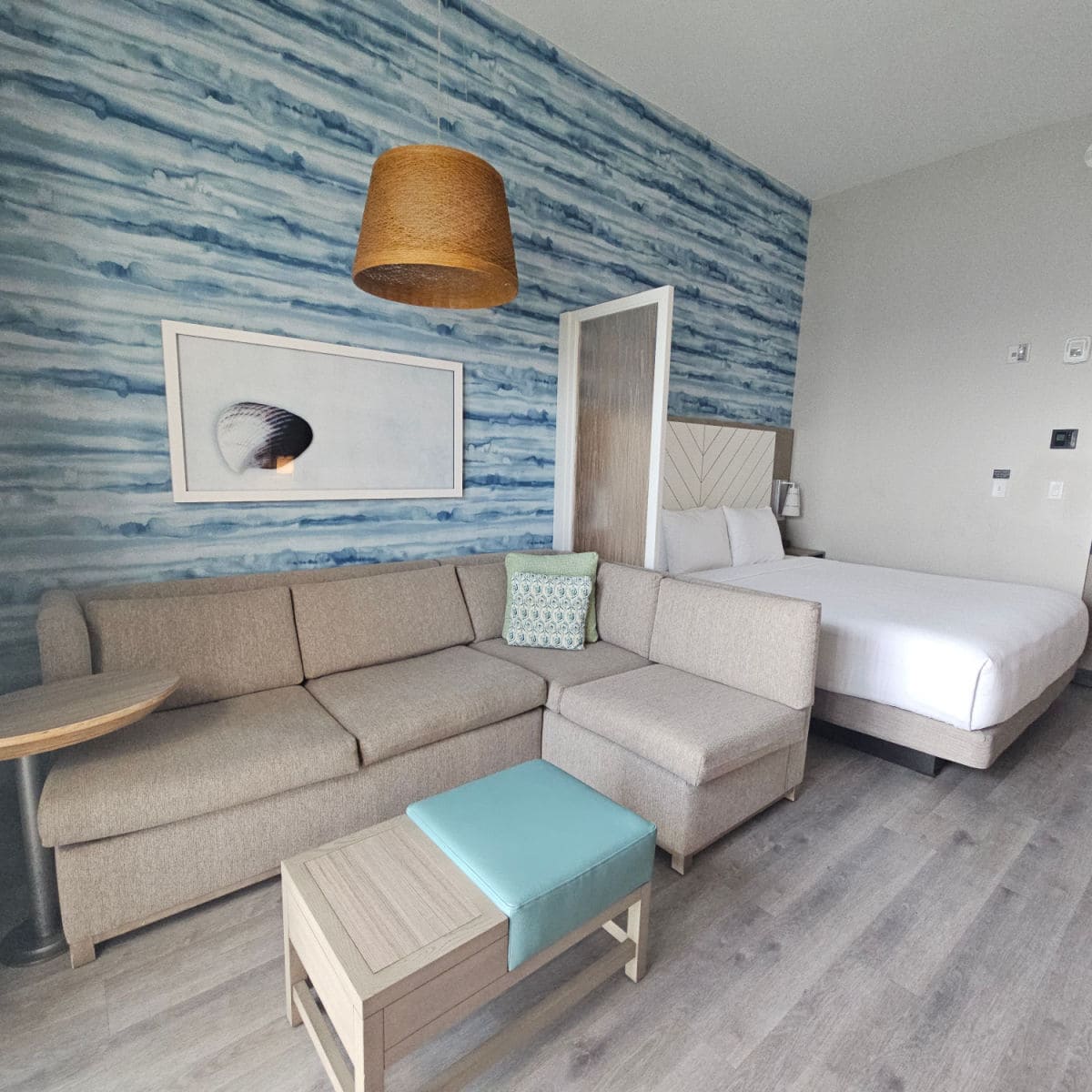 king suite with couch and footstool and king bed, blue and white wall print with shell photo