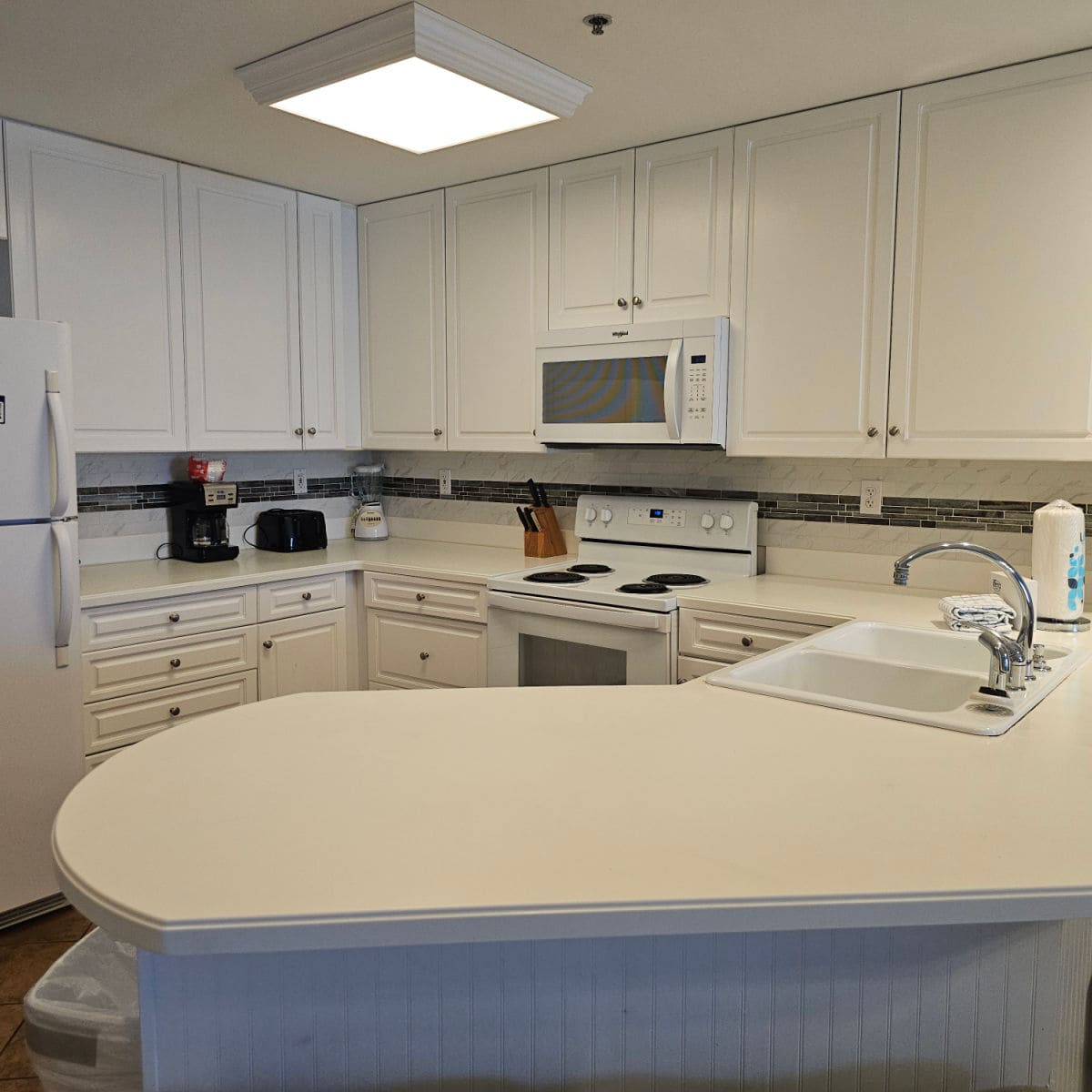 Kitchen with white cabinets and appliances, coffee maker and toaster on the counter
