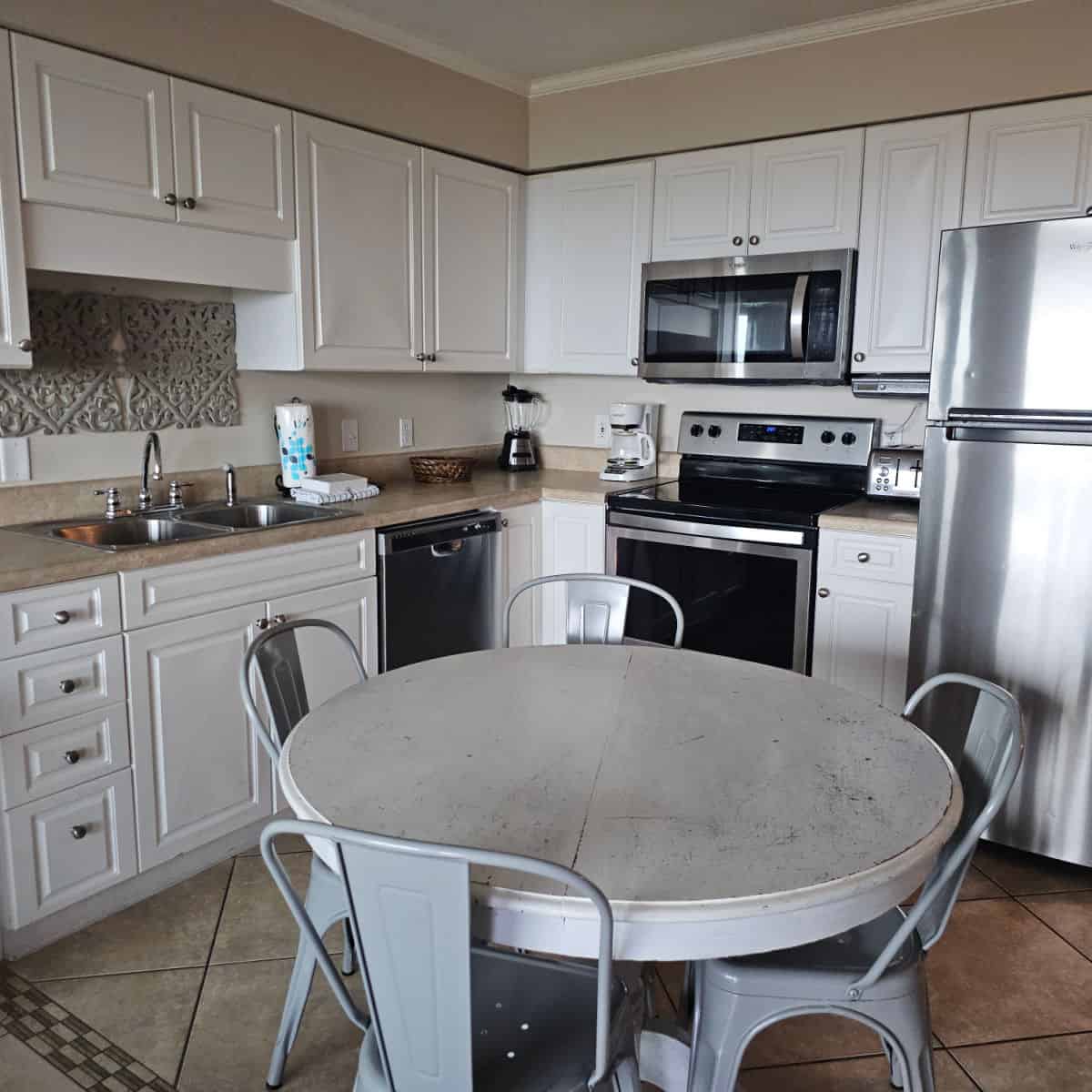 kitchen with white cabinets and stainless steel appliances, kitchen table with 4 metal chairs around it
