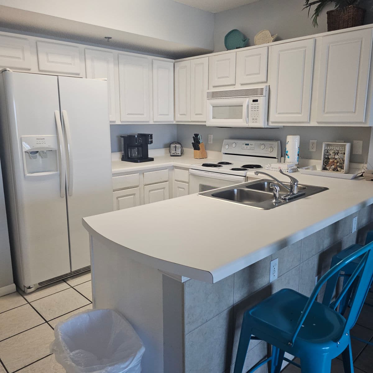 white kitchen cabinets and appliances, blue chairs at the counter