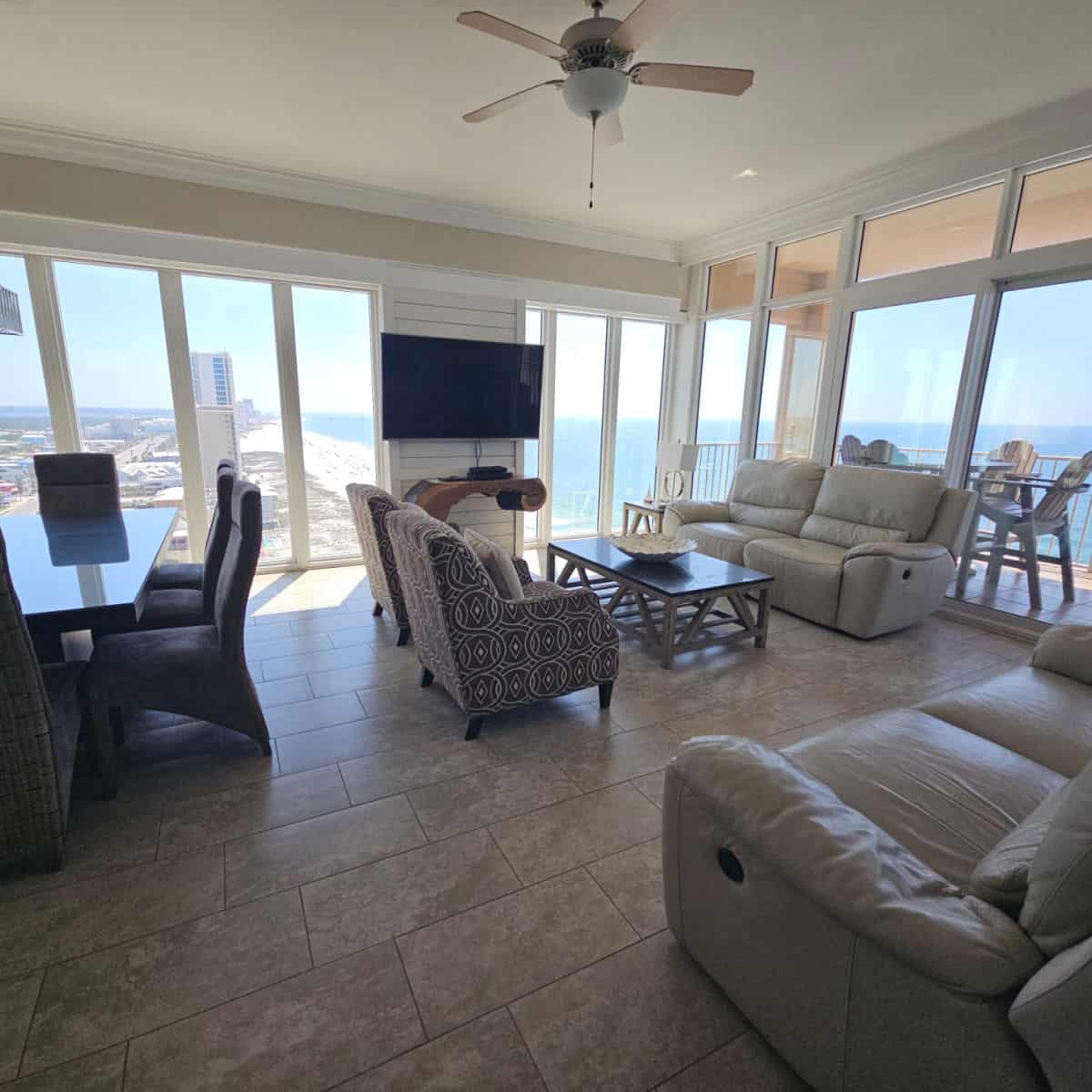 dining and living room area with couches and chairs, wrap around windows with views of Gulf Shores and the Gulf