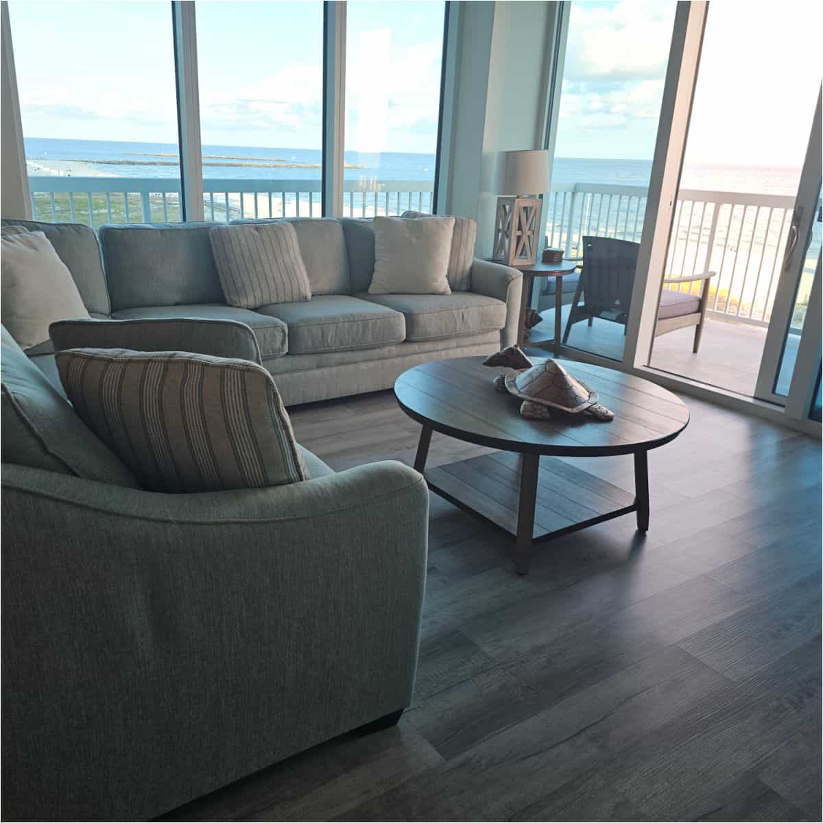 couch and grey chair near a large picture window lookingout over the water.