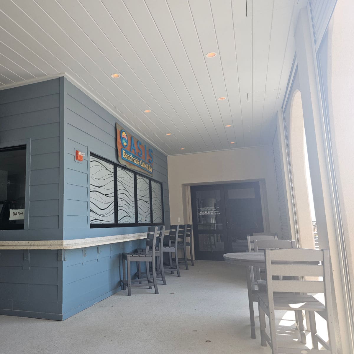 Oasis Beachside Cafe and Bar sign over the order window, tall bar stools by the counter
