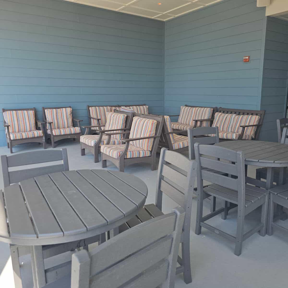 tables and chairs under a cover, some of the chairs have striped cushions on them