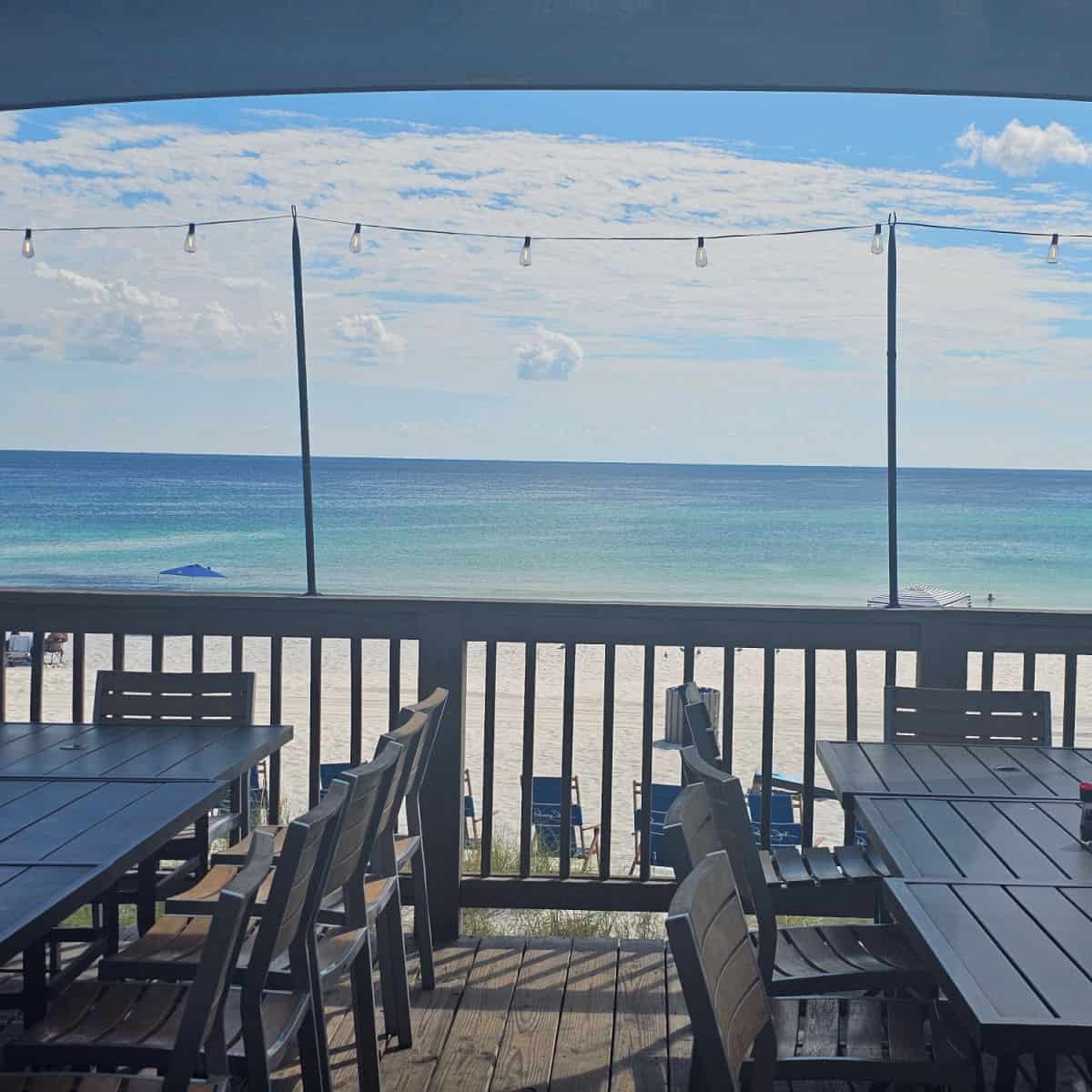 looking over tables and chairs to a white sand beach and gorgeous Gulf waters