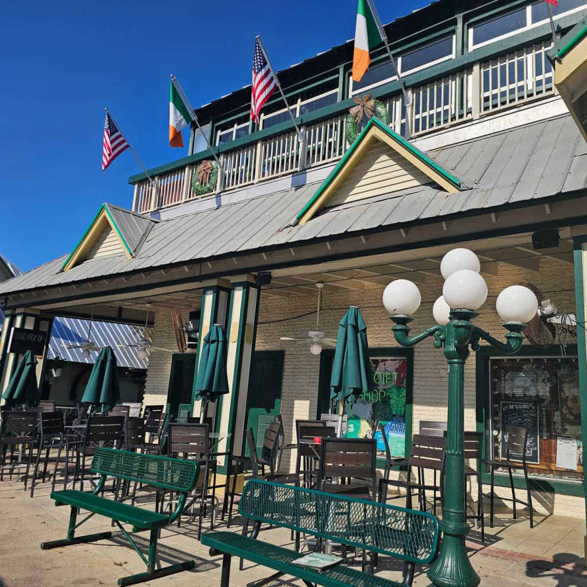 McGuire's Destin exterior with green lamppost and white lights, green benches, tables and chairs