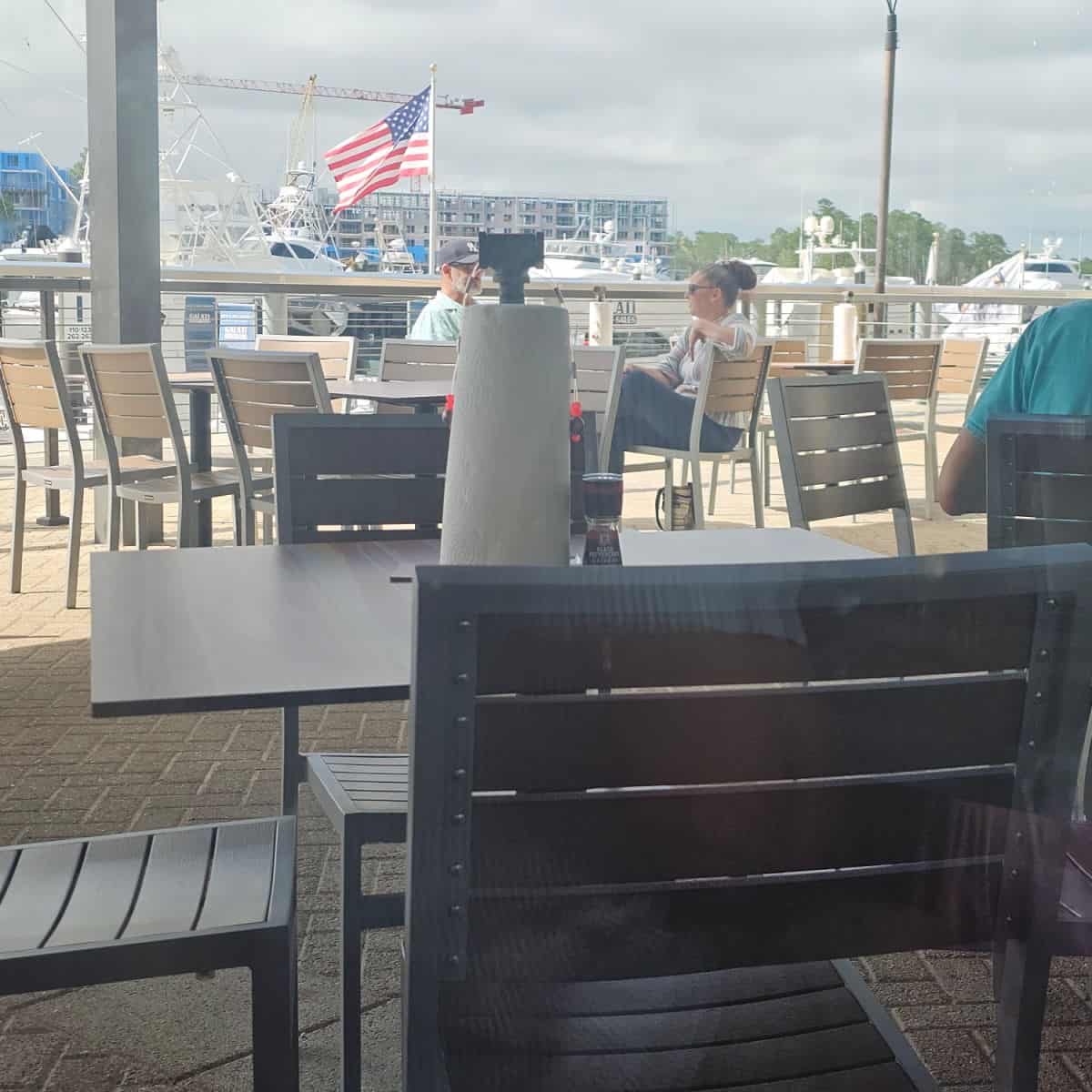 outdoor seating with paper towels on the table, boats and Margaritaville Orange Beach in the background