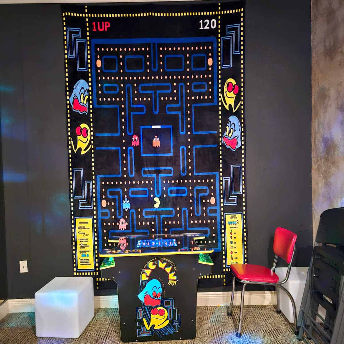 pacman wall art above a game of pacman with two chairs