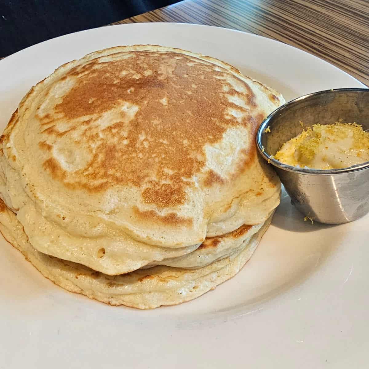 pancakes on a white plate with a cup of lemon butter
