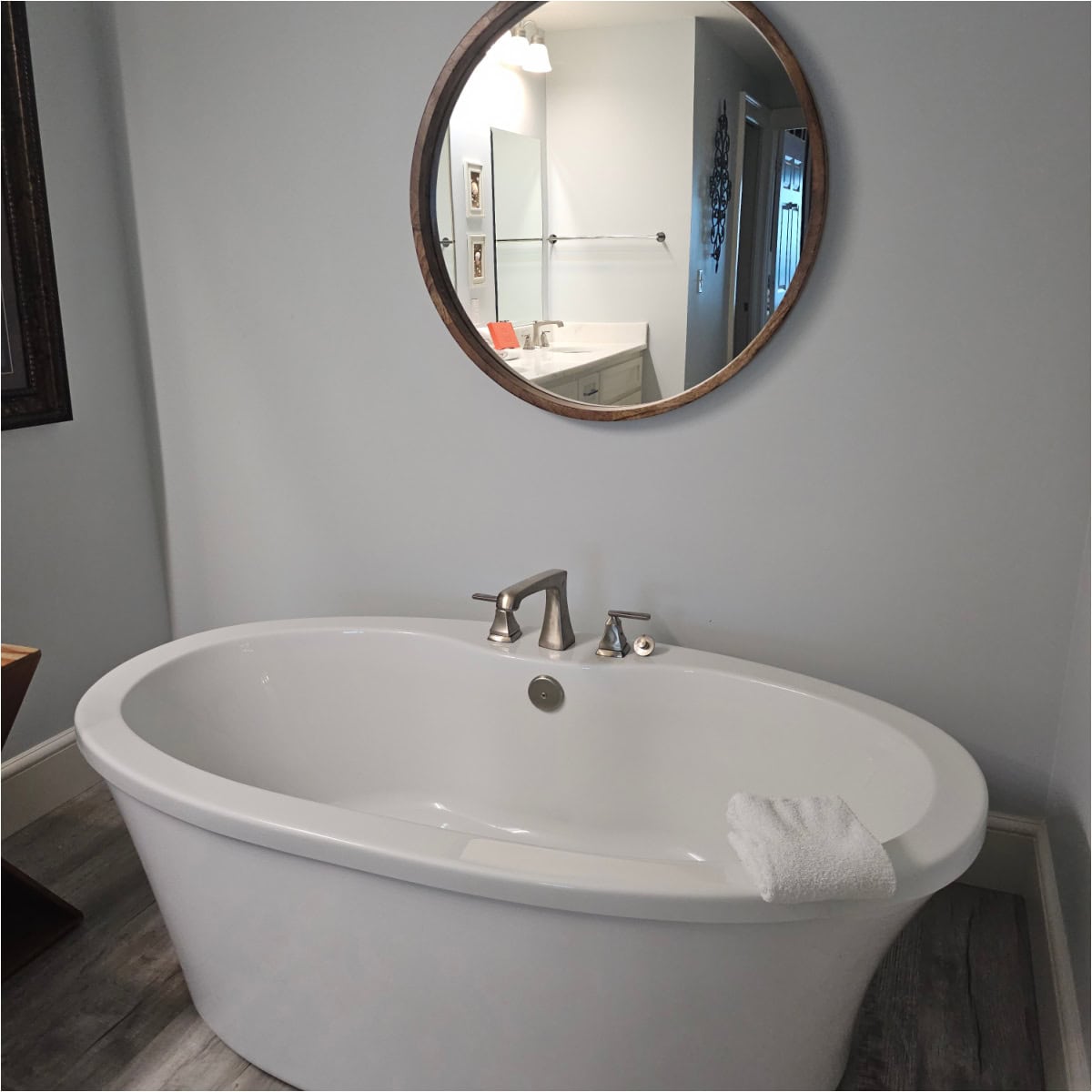 White deep soaking tub with a large mirror above the tub