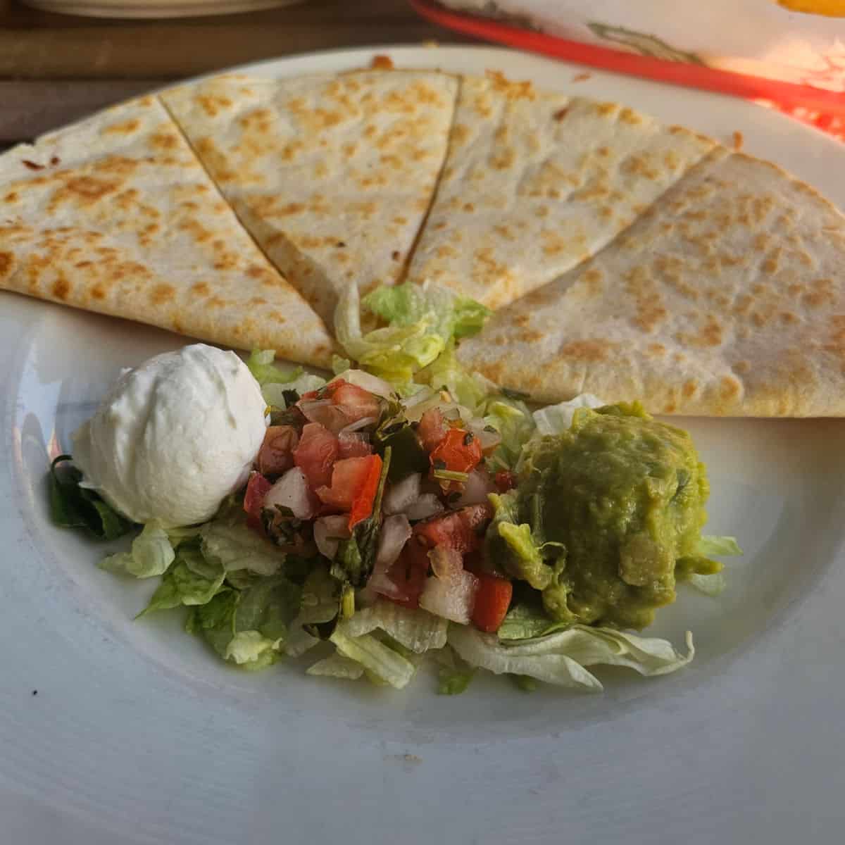 quesadilla and quac and sour cream on a white plate