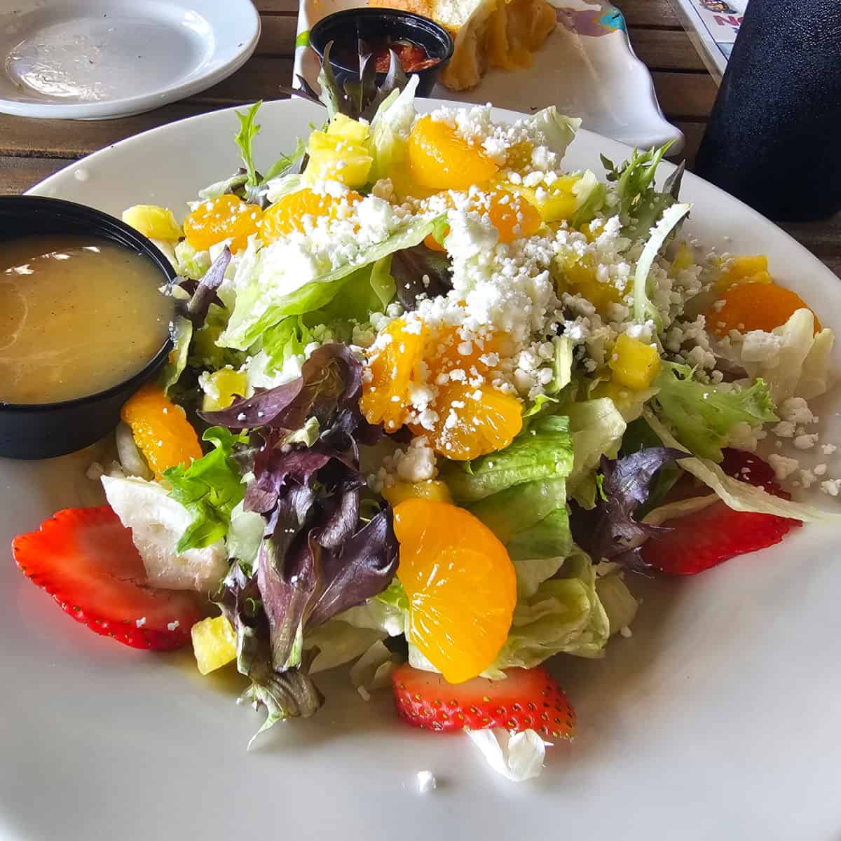 salad with orange pieces and strawberries on a white plate