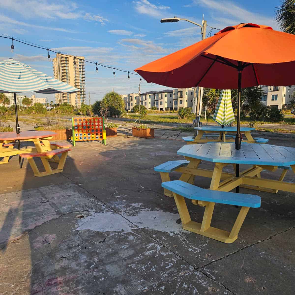 picnic tables and games on a concrete area with condos in the background