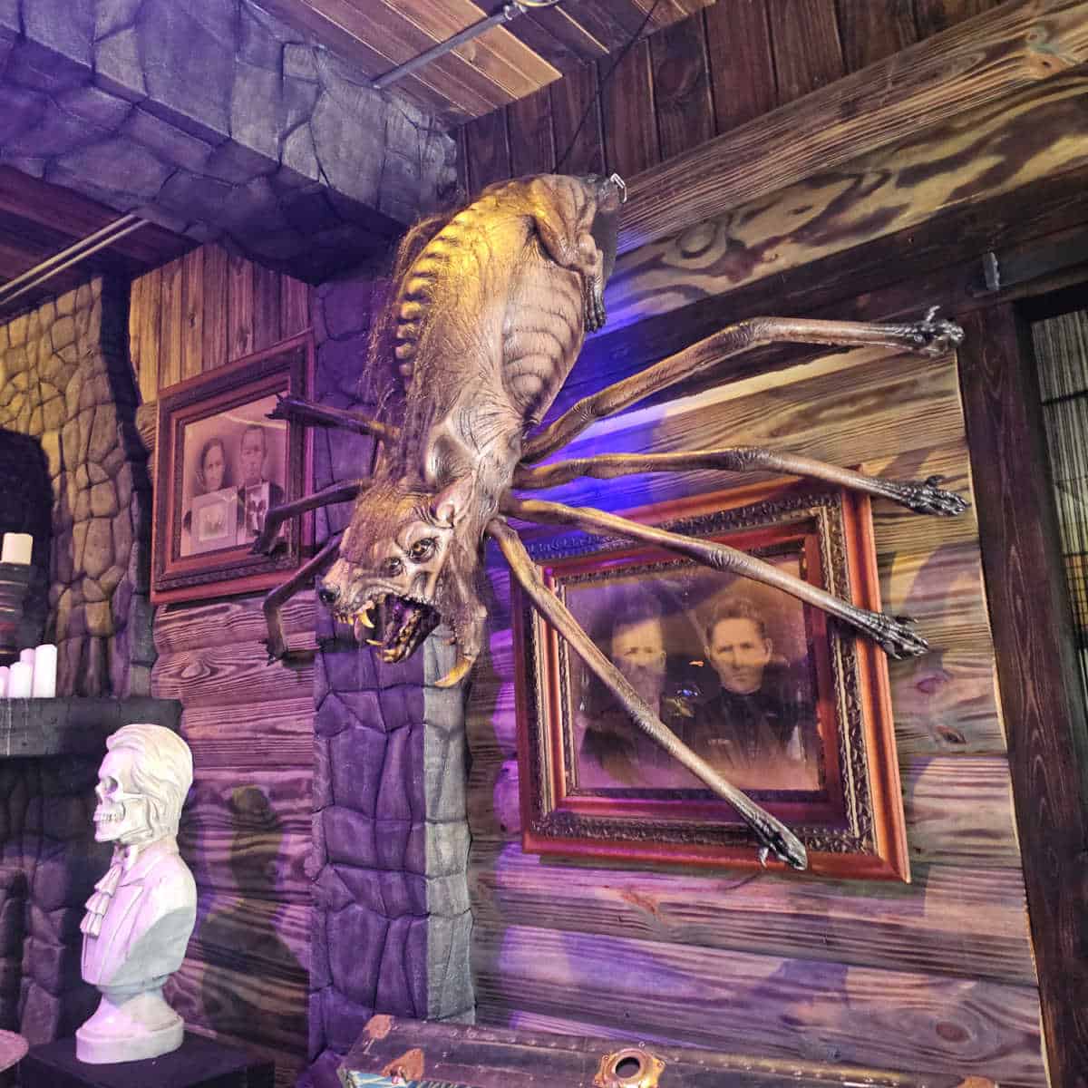 werewolf spider coming out of the wall with a family photo behind it, skull bust on the side