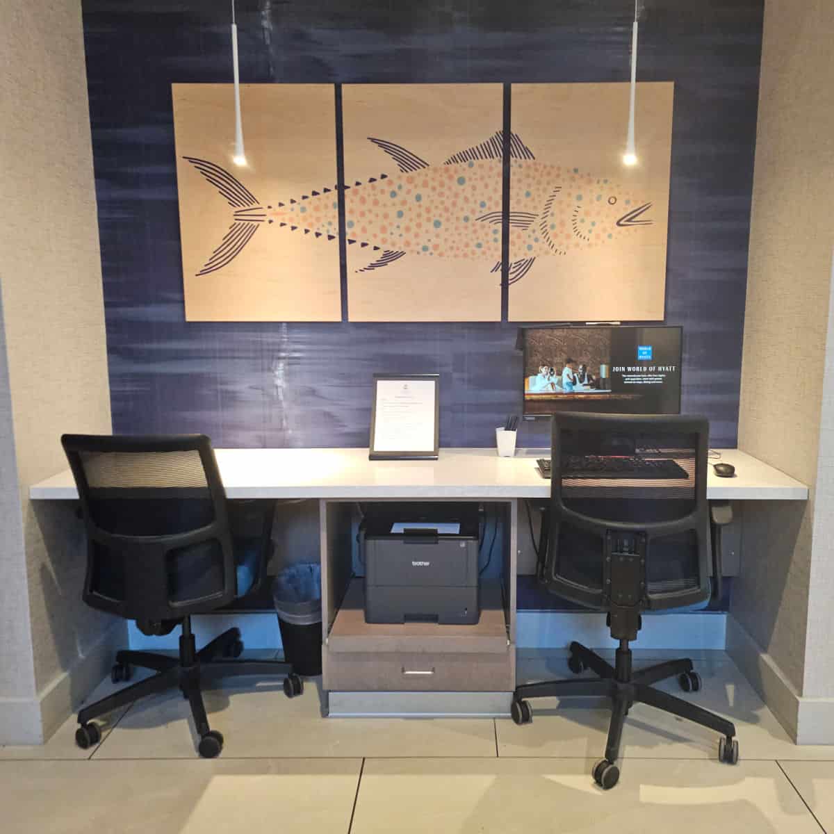 computer with two chairs at the desk, fish art above the computer