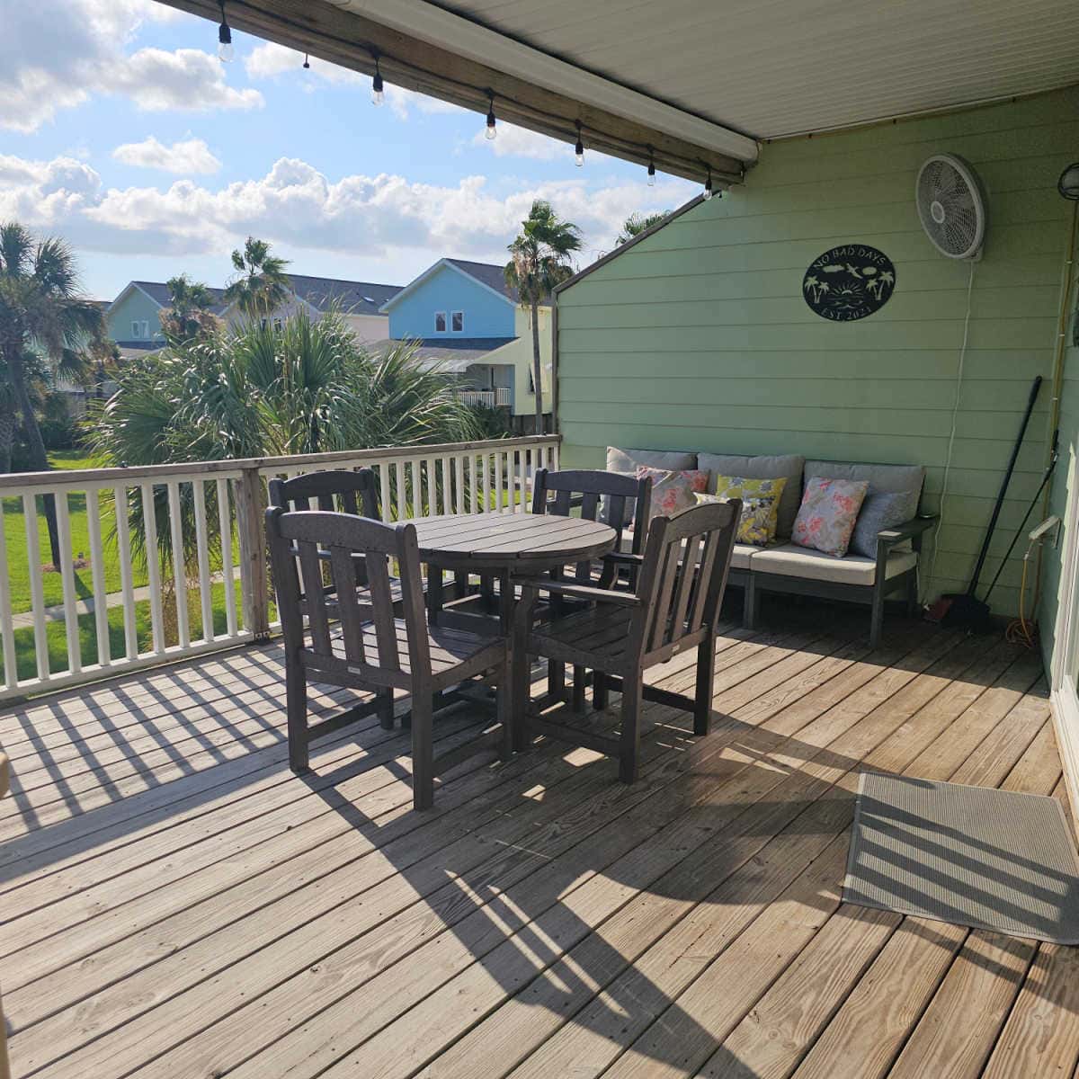 Deck with table and chairs, couch with pillows looking out towards colorful houses