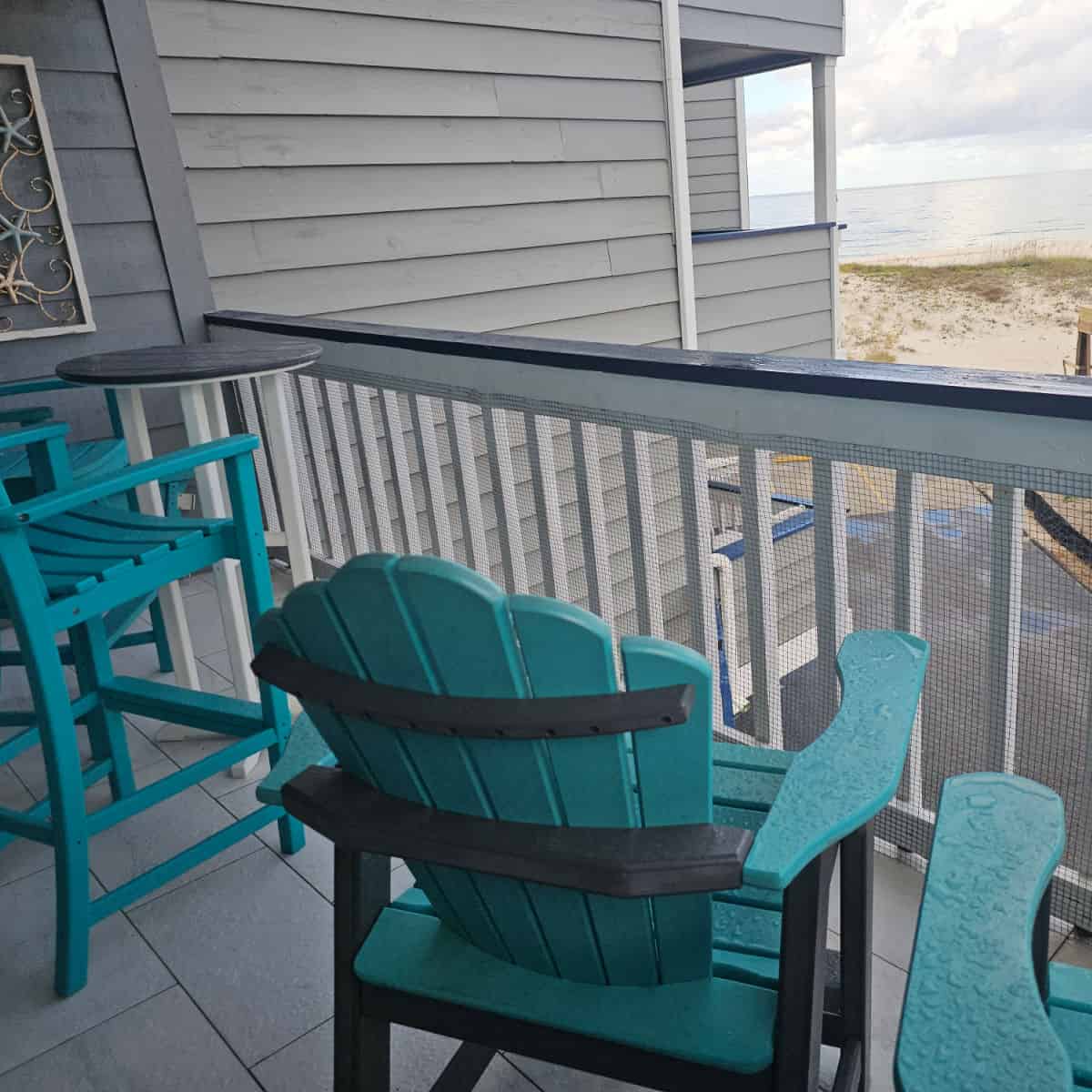 Balcony with blue Adirondack chairs looking out towards the Gulf