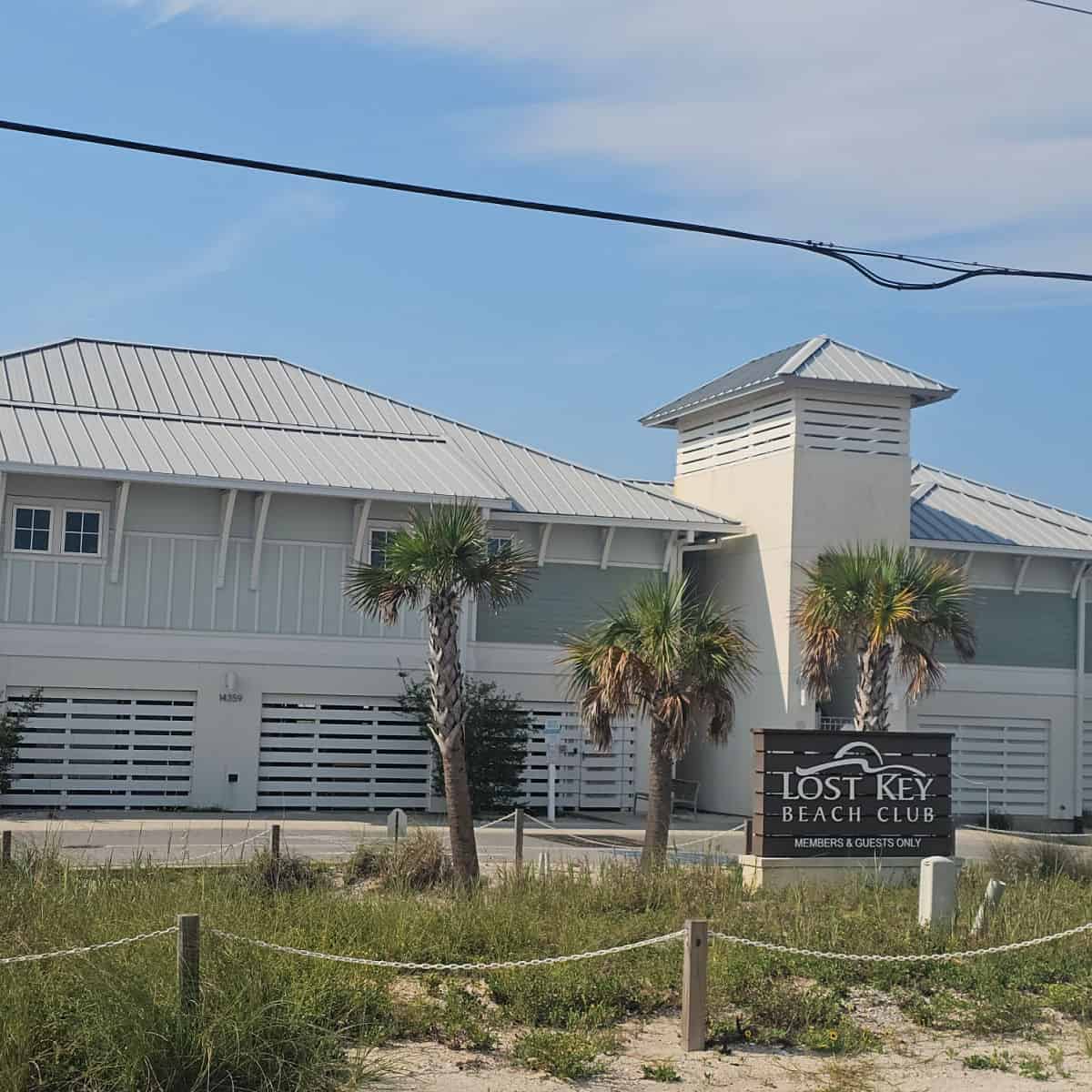 Lost Key Beach Club Members & Guests Only sign in front of a two story building with palm trees